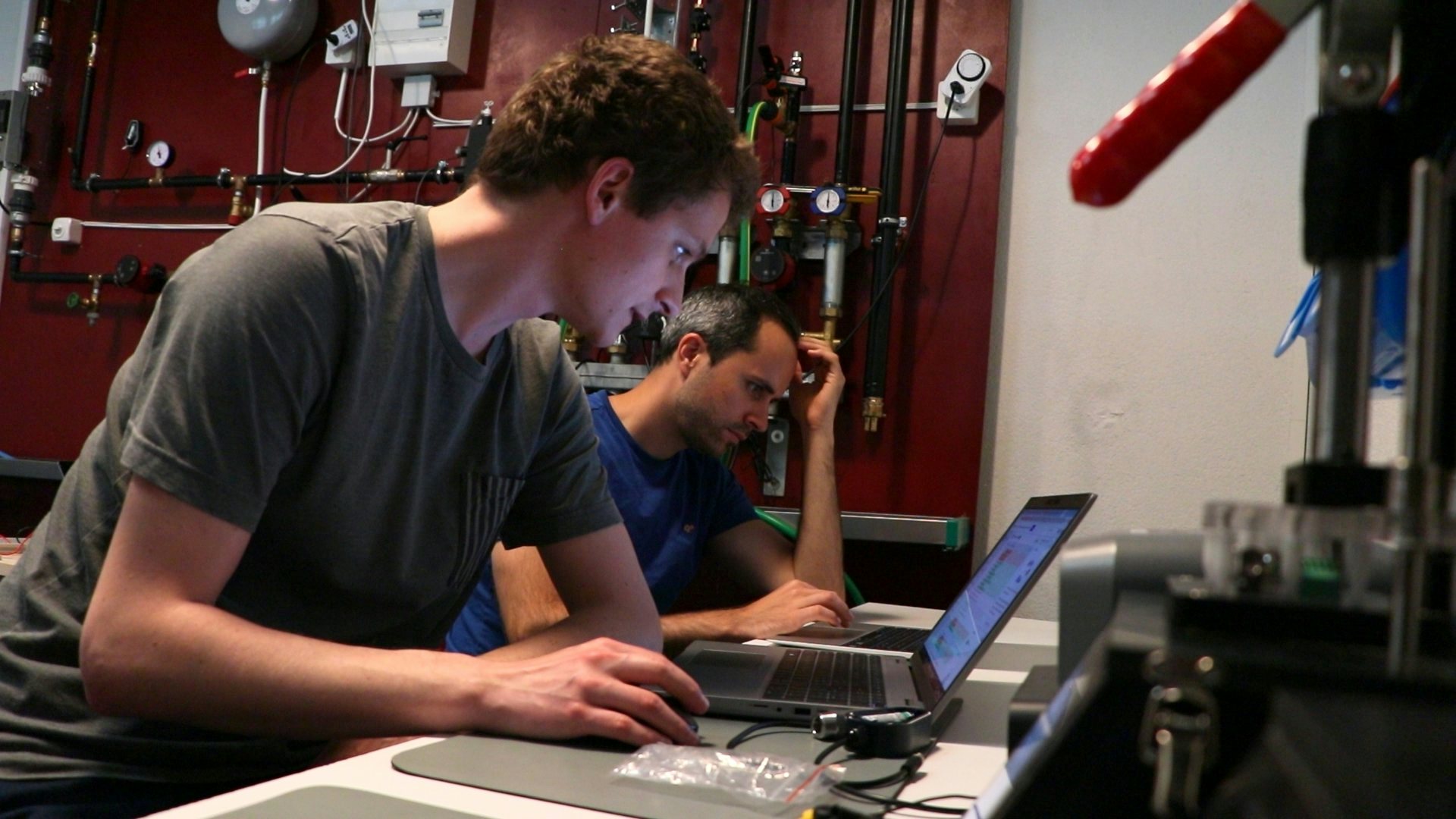 deux hommes travaillant sur leur ordinateur dans un local technique